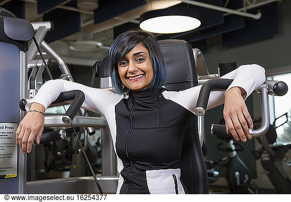 A paraplegic woman posing for the camera after working out using an overhead press in a fitness facility; Sherwood Park  Alberta  Canada