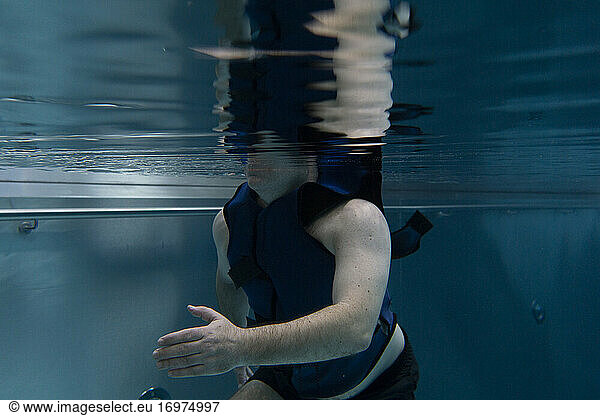 a patient with a floating vest does physiotherapy in a swimming pool