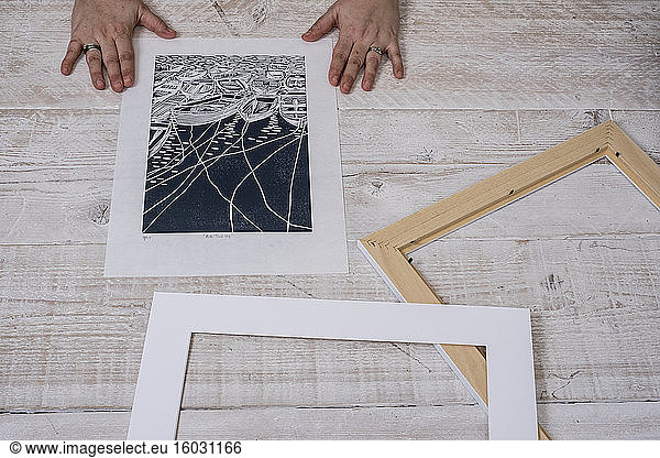 A person framing a lino cut into a border and picture frame.