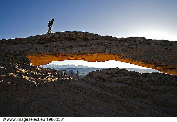 A person hiking on top of an arch  Canyonlands National Park  Utah.