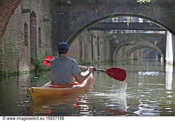 A person kayaking along a canal in Europe