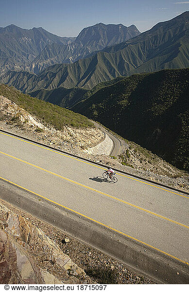 A person riding his bike on a road of a mountainous landscape. Queretaro  Mexico.