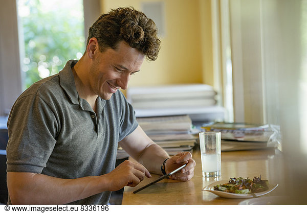 A person sitting alone in a cafe. A man using a digital tablet.