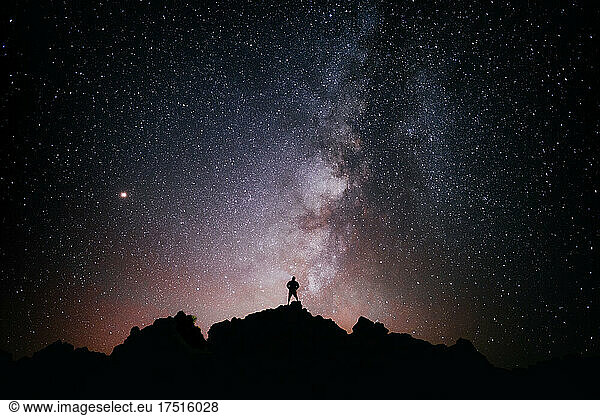 A person standing looking at the star field and the milky way