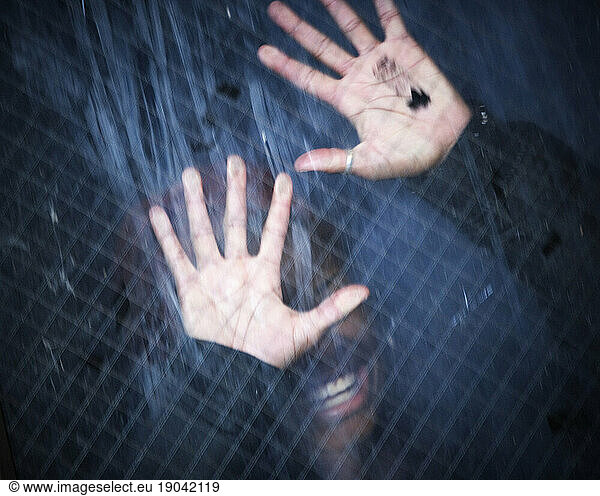 A person with their hands pressed against a window.
