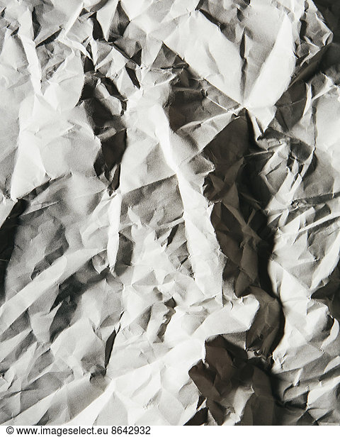 A piece of recycled white paper  crumpled and scrunched up  refuse.