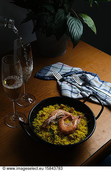 a plate of Spanish paella prepared for two accompanied by two glasses