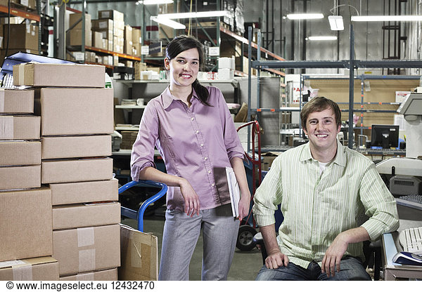 A portrait of a team of two Caucasian male and female workers in a parts department work site