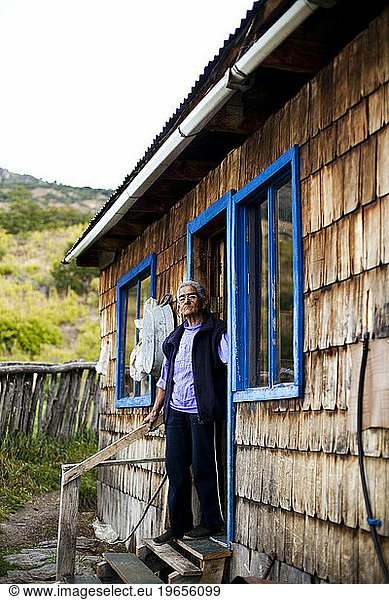 A portrait of a woman on her doorstep of her home.