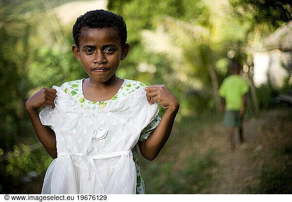 A portrait of a young Fijian girl holding her favorite while dress.