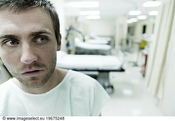 A portrait of a young man sitting in a hospital room.