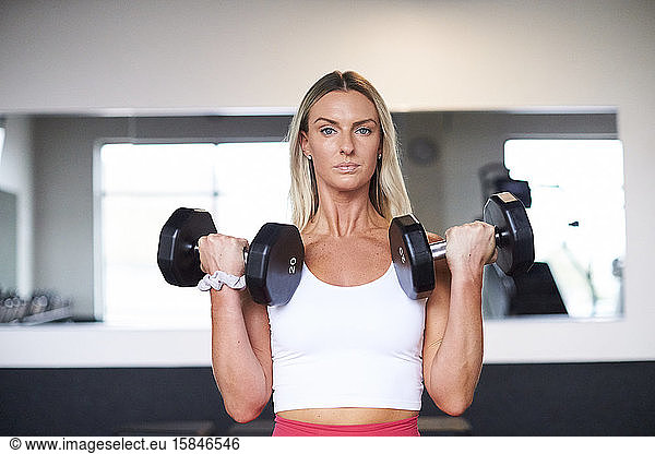 A portrait of an athletic blonde lifting weights.