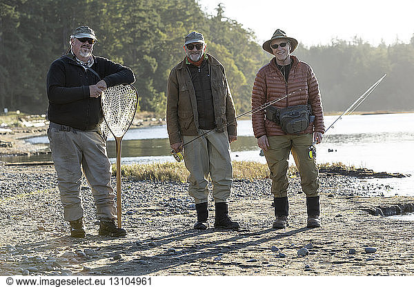 A portrait of two Caucasian male fly fishermen and their fly fishing guide standing on a beach on the west coast of the USA