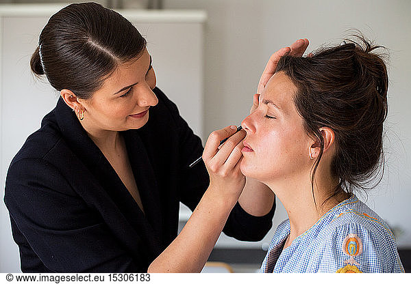 A professional make up artist at work  creating a look for a young woman.