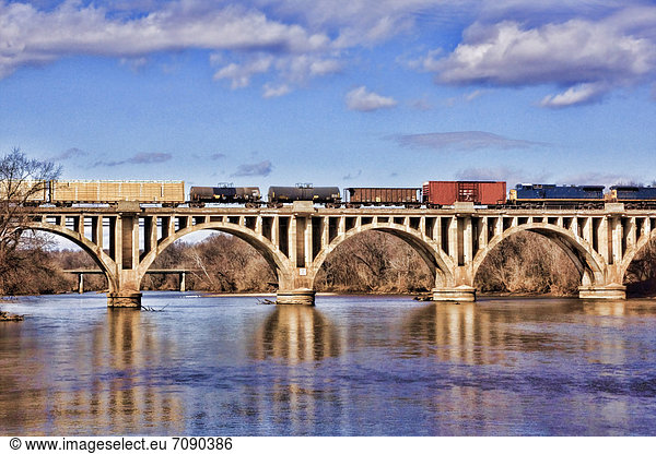 A railway bridge over a river. Arched spans  with a long freight train with wagons going over the top. Rappahannock River.