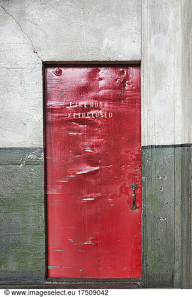 A red barrier fire door in a museum  notice Fire Door Keep Closed  dents and marks on the metal