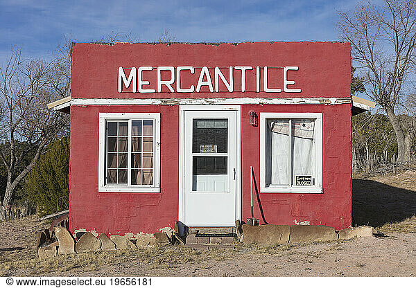 A red painted building frontage  with a sign MERCANTILE  windows boarded up.