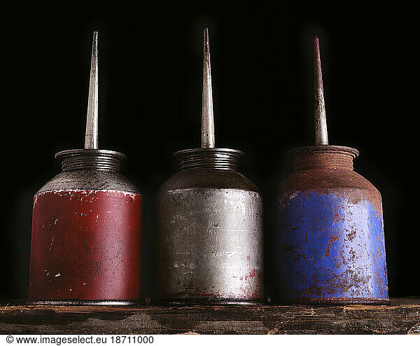 A red  white and blue colored oiling cans.