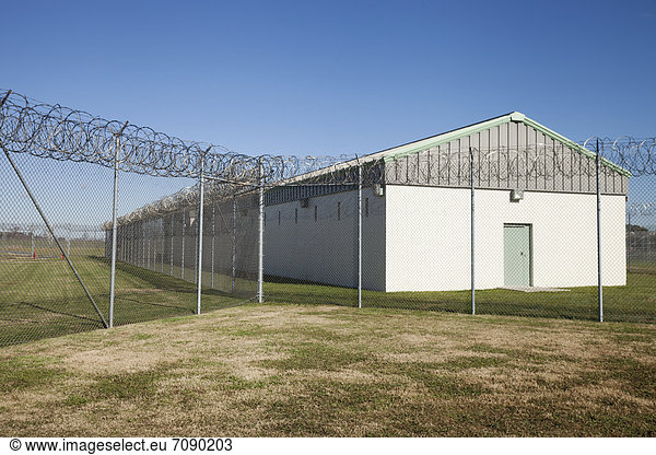 A residential unit  wing or dormitory building for prisoners at aCorrectional Facility. Fence with razor wire.