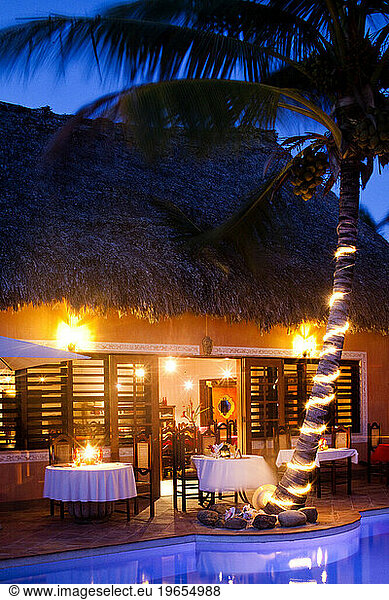 A restaurant is lit up near a pool at a luxury hotel in Belize.