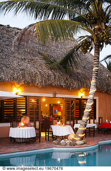 A restaurant is lit up near a pool at a luxury hotel in Belize.