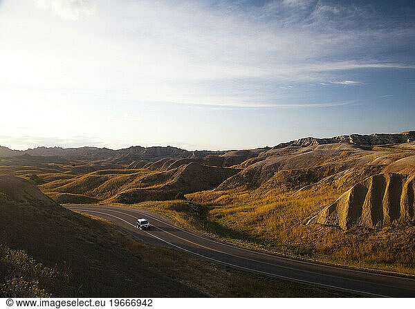 A road winds through the Badlands National Park  SD during sunset.