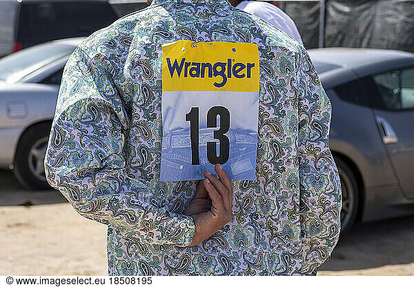 A rodeo participant adjusts his number backstage at the a black rodeo