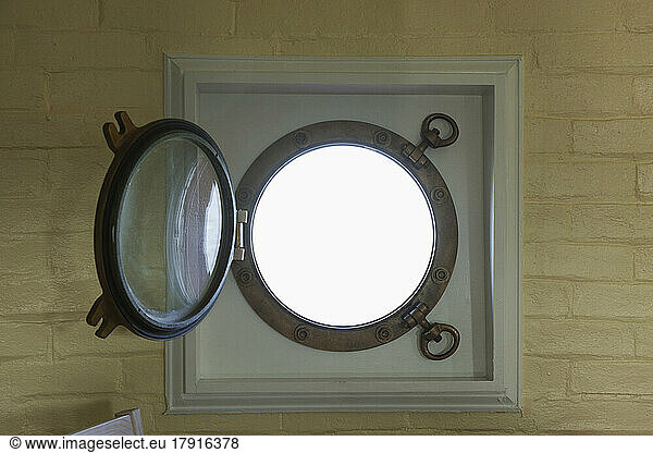 A round window  metal frame and a round glass porthole  open.