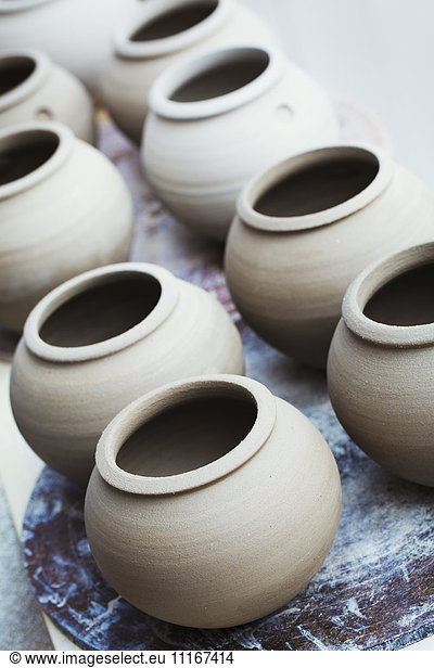 A row of handthrown pots  vases with round tops.