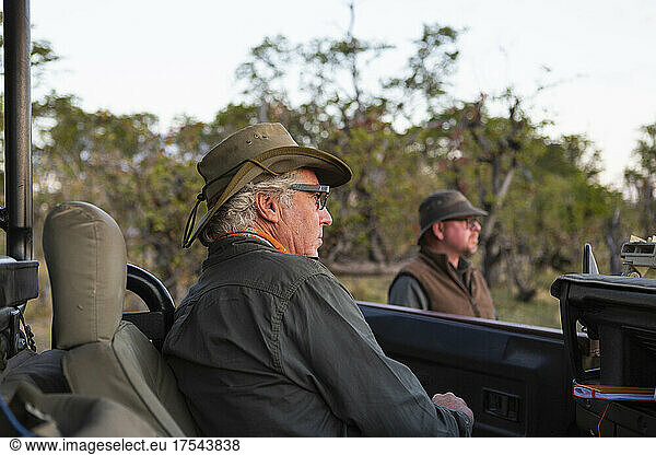 A safari guide and a man by a jeep.