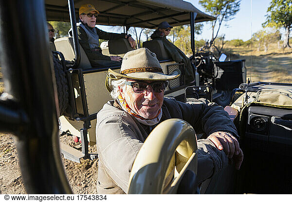 A safari guide by a jeep on a sunrise drive.