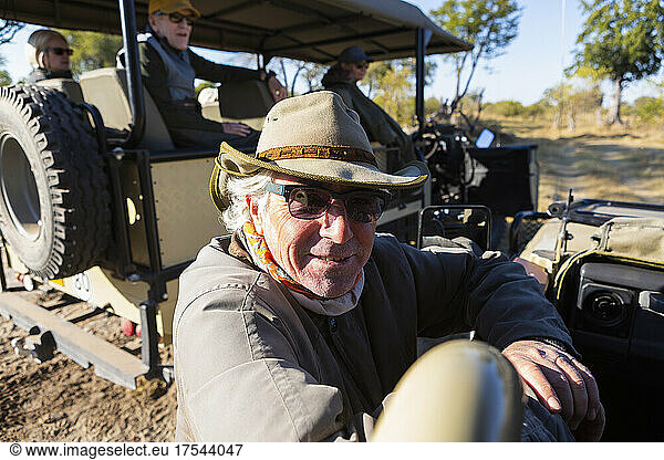 A safari guide by a jeep on a sunrise drive.