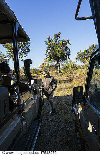 A safari guide by a jeep on a sunrise drive through a wildlife reserve.