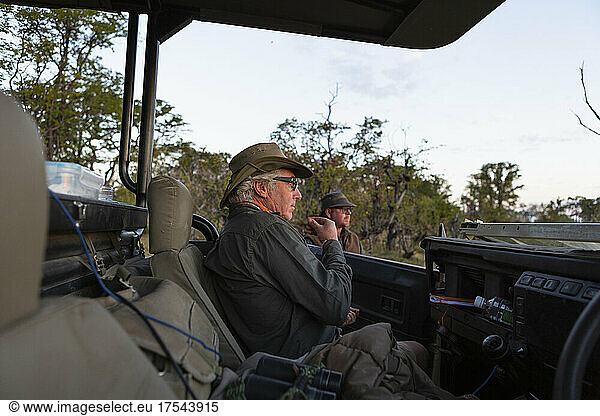 A safari guide seated in a jeep on a dawn drive.