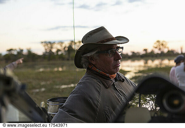 A safari guide seated in the driving seat of a jeep.