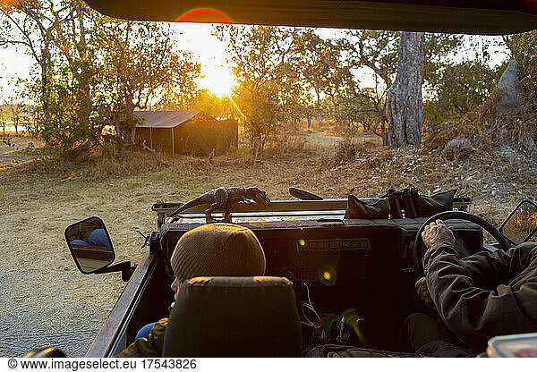 A safari jeep  view of the dirt road ahead at sunrise  lens flare