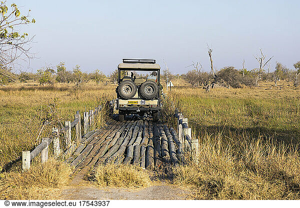A safari vehicle crossing a bridge in the landscape of swamps and waterways.