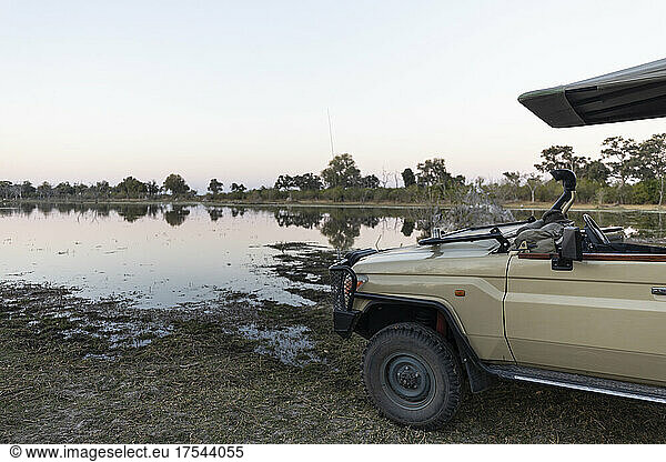 A safari vehicle parked by a waterway in the Okavango Delta