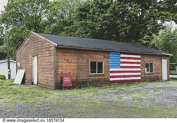 A Sale Today A board and an American flag painted on empty building on a street in a small town.