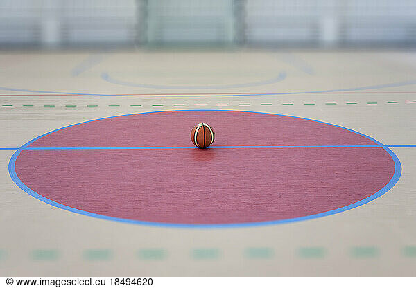 A school sports hall with a marked indoor football pitch  a striped blue and yellow ball in a pink circle.