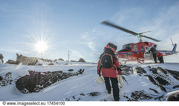 A scientist carries samples to a helicopter on a volcano in Antarctica