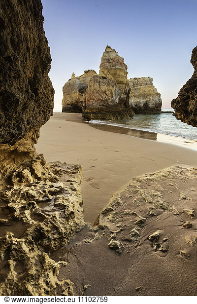 A sea cave frames the ocean and the imposing cliffs at dawn  Praia da Rocha  Portimao  Faro district  Algarve  Portugal  Europe