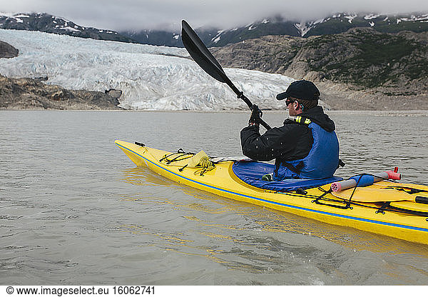 A sea kayaker approaches a glacier terminus where the ice meets the sea.