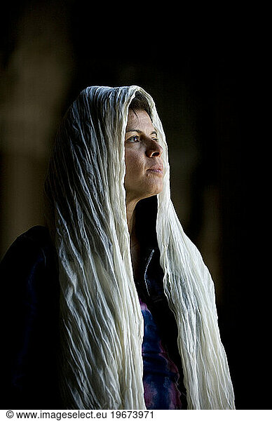 A shawl covered woman stares out the window of a grand mosque.