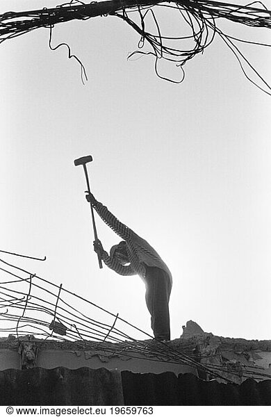A silhouette of a construction worker swinging a sledge hammer.