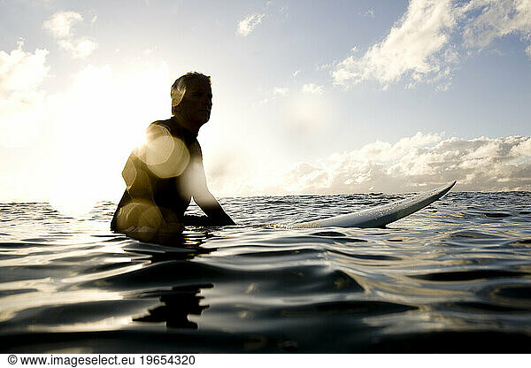 a silhouette of a surfer sitting on his board
