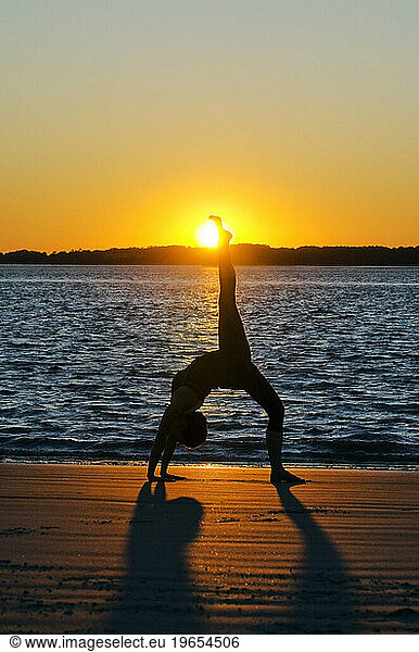 A silhouette of a woman performing yoga on the beach at sunset on Hilton Head Island  SC.