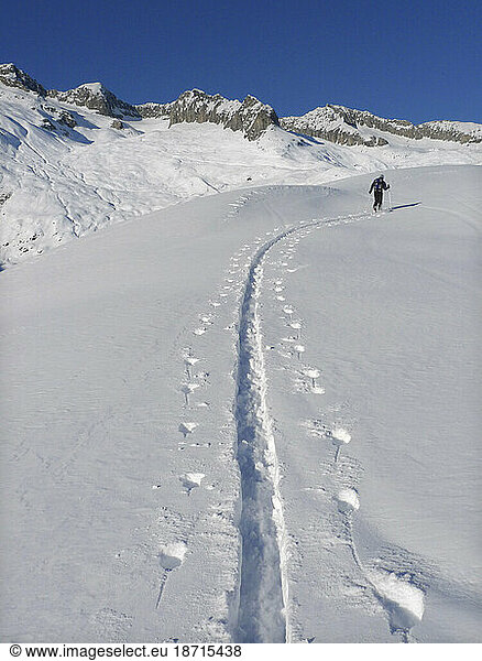 A ski mountaineer is hiking in the backcountry of the Swiss Walliser Alps.