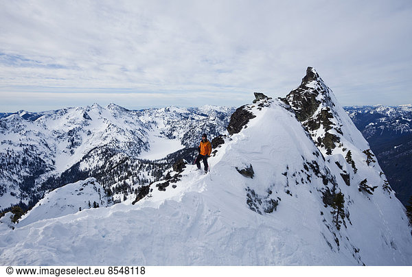 A skier on a ridgeline  pausing before skiing The Slot on Snoqualmie Peak in the Cascades Ranges  Washington state  USA.