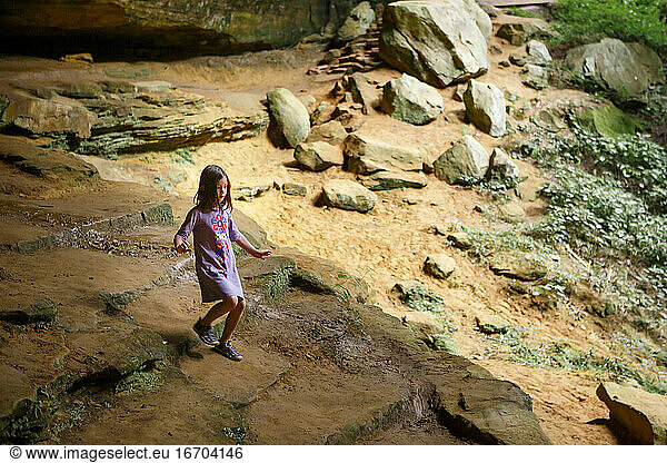 A small child walks down a stone staircase in a sunlit sandstone gorge
